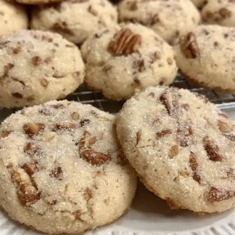 Close-up of a pecan sandie broken in half, showing crumbly, tender texture.