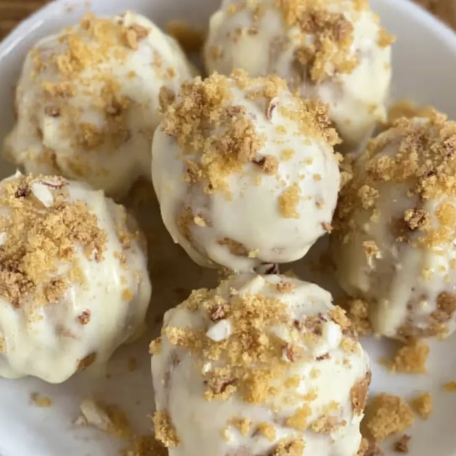 Pumpkin pie balls coated in white chocolate and sprinkled with graham crumbs.