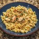 Fork lifting buttery noodles with chicken pieces